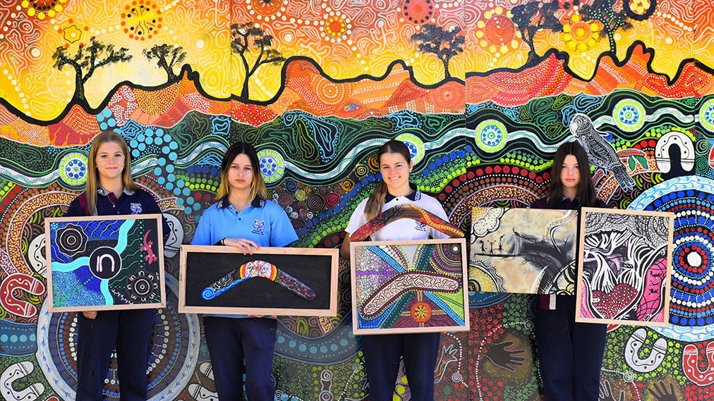 four deadly arts students holding their artworks